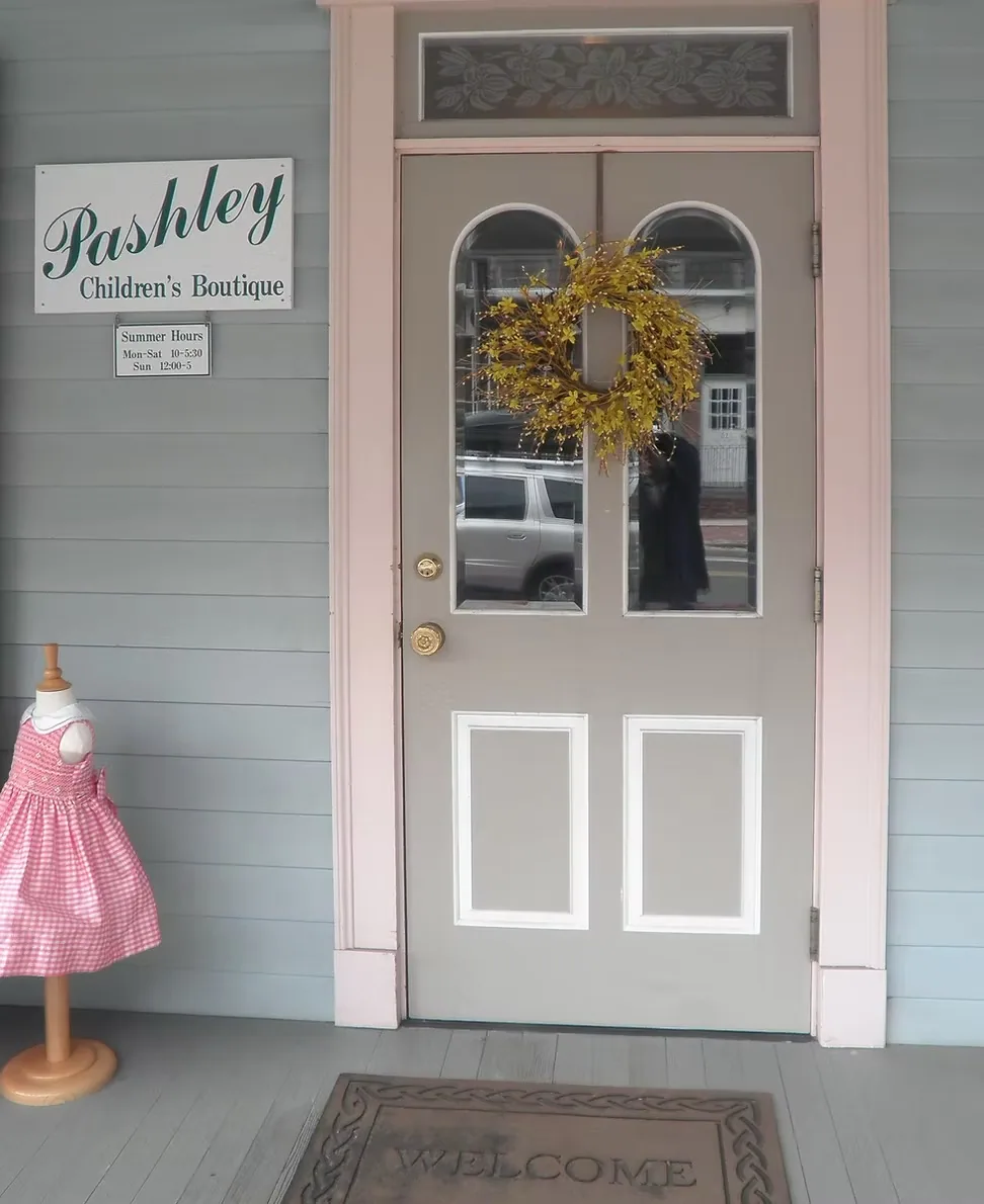 The taupe front door of Pashley with two arched windows and a welcome mat.